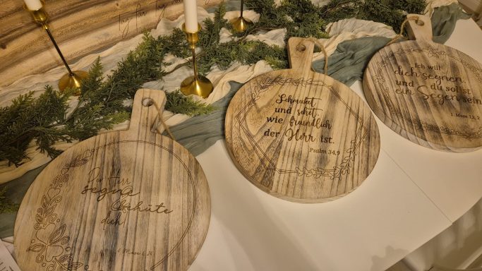 Drei runde Holzbrettchen mit eingravierten Beschriftungen und dekorativem Grüngemüse.