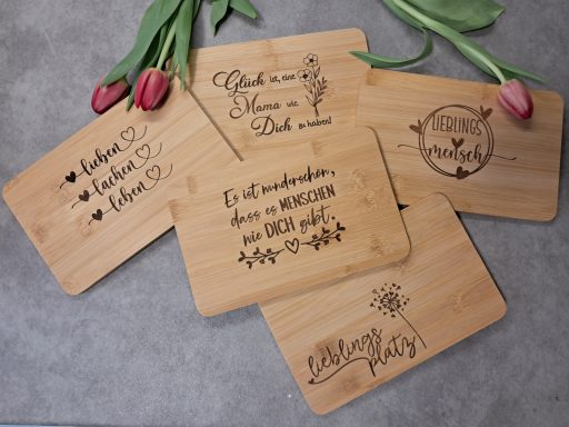 Holzplatten mit verschiedenen gravierten Motiven und Texten, umgeben von Tulpen.