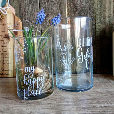 Zwei dekorative Gläser, eines mit Blumen und eines mit dem Schriftzug „My Happy Place“.