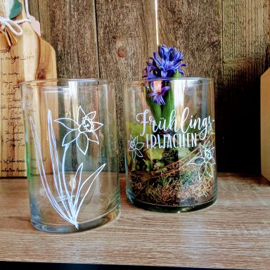 Zwei Glasbehälter mit Blumenmuster, einer mit einer blühenden Hyazinthe.