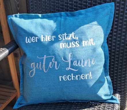 Blauer Kissenbezug mit dem Schriftzug "guter Laune" und einem Spruch darüber.