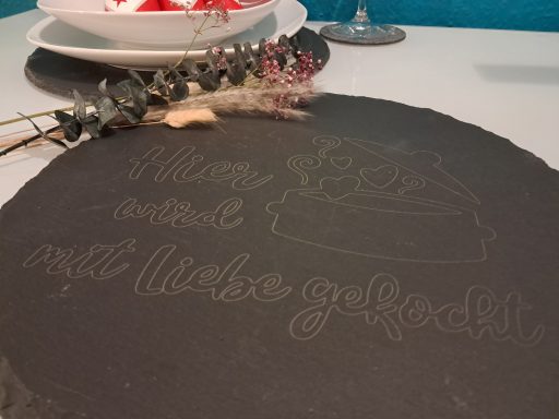 Ein schwarzes Tablett mit einer künstlerischen Gravur von einer Torte und dem Schriftzug "Wie lecker!"