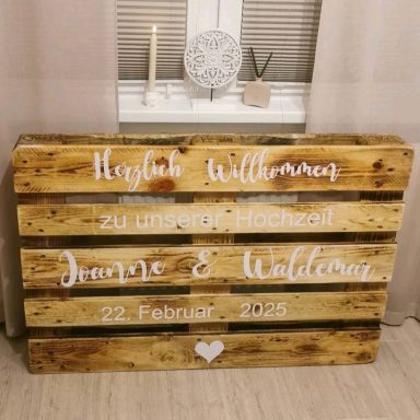 Rustikales Holzschild mit den Namen und Datum einer Hochzeit.
