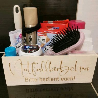 Eine Holzkiste mit Toilettenartikeln und einer Haarbürste, beschriftet "Bitte bedient euch!"