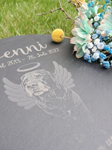Grabschrift mit Engel und Blumen, Gedenkdatum für Jenni, auf schwarzem Hintergrund.