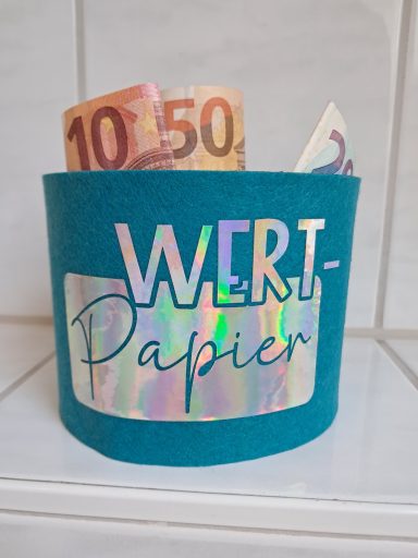 Ein tealfarbener Behälter mit einem reflektierenden Aufkleber und Geldscheinen darin.