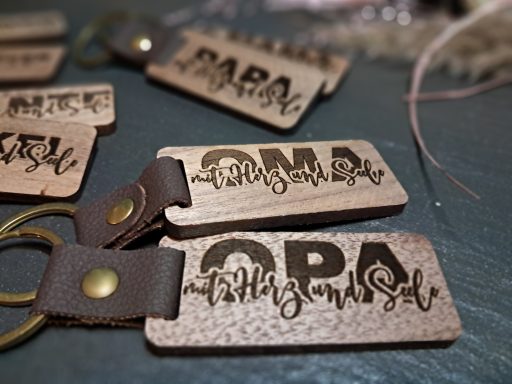Holzschlüsselanhänger mit "Oma" und "Opa" in geflochtenen Schriftzügen.