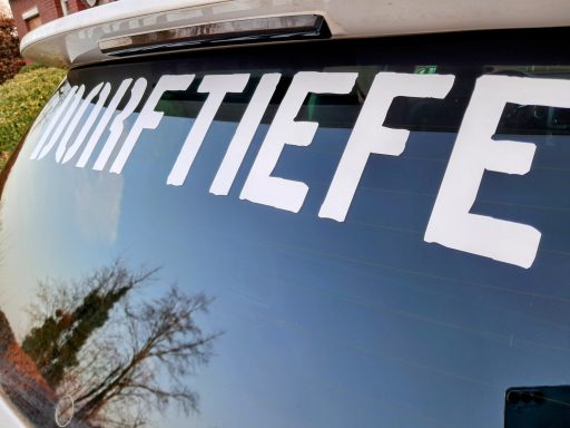 Aufkleber mit dem Wort "Bodentiefe" auf einer Fahrzeugheckscheibe.
