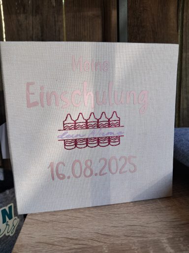 Brett mit der Aufschrift "Einschulung 16.08.2025" und bunten Häusern.